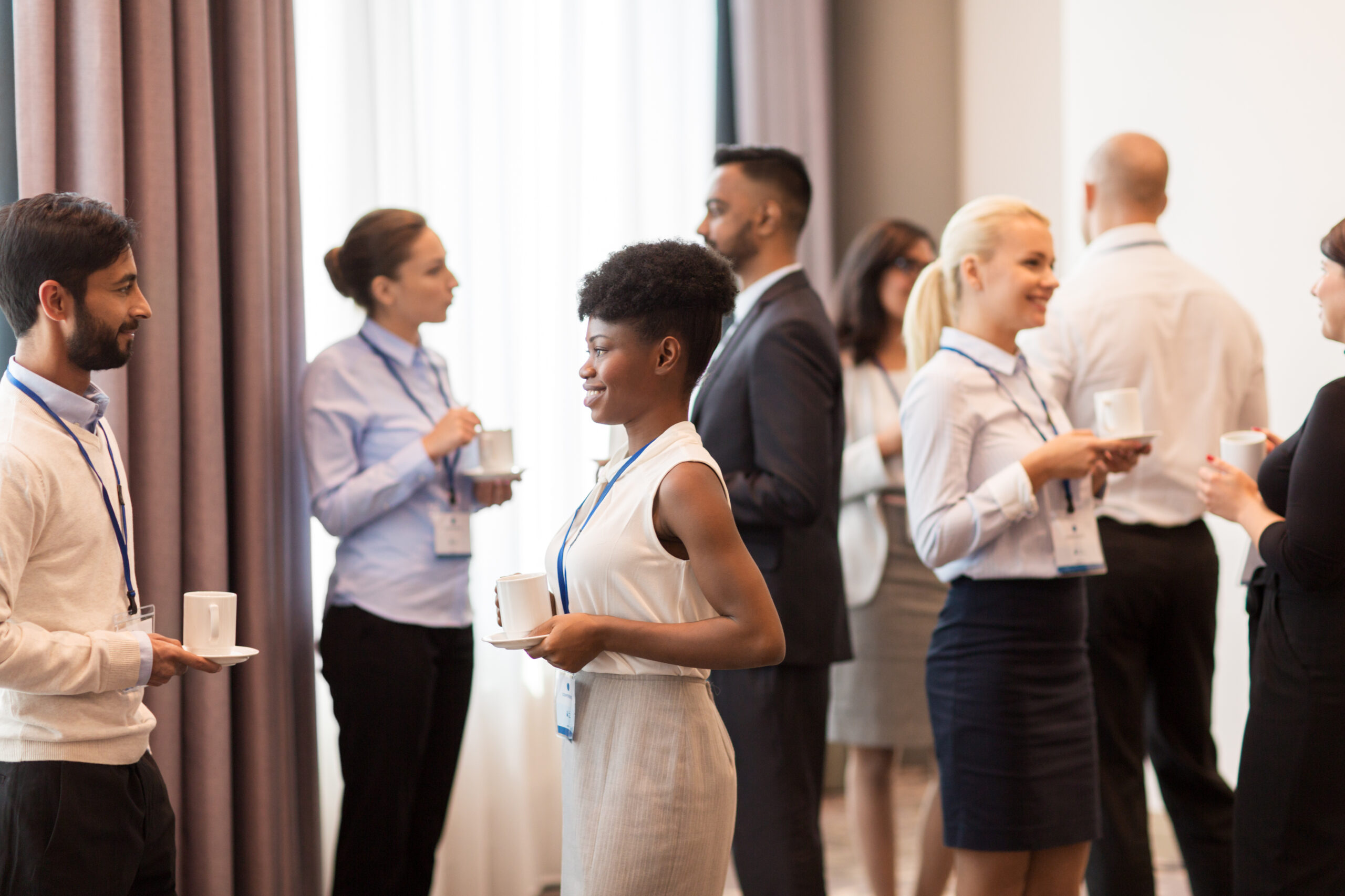 business and education concept - international group of people with conference badges drinking coffee