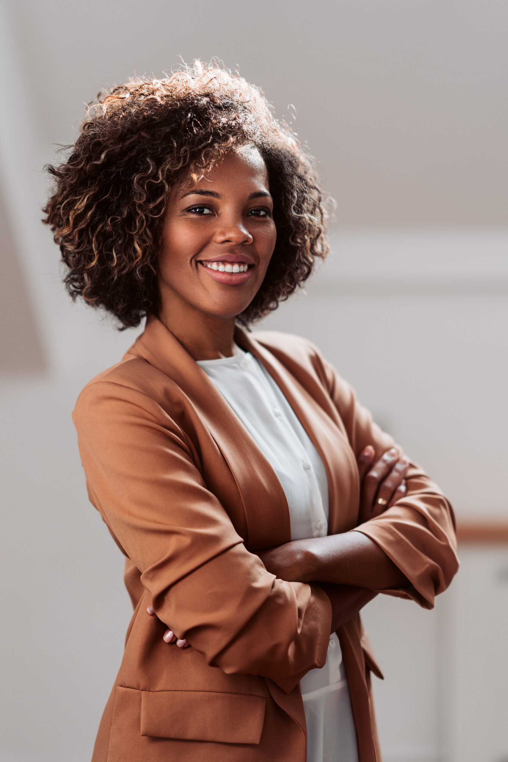 Portrait of young cheerful african american businesswoman wearing brown suit smiling and looking at camera