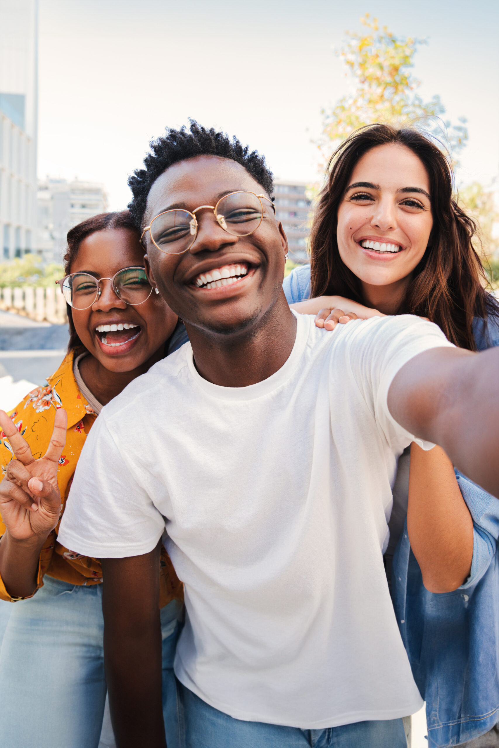 Vertical portrait of a group of multiracial young student people smiling taking a selfie together. Happy african american teenager laughing with his cheerful friends. Classmates on friendly meeting. High quality photo